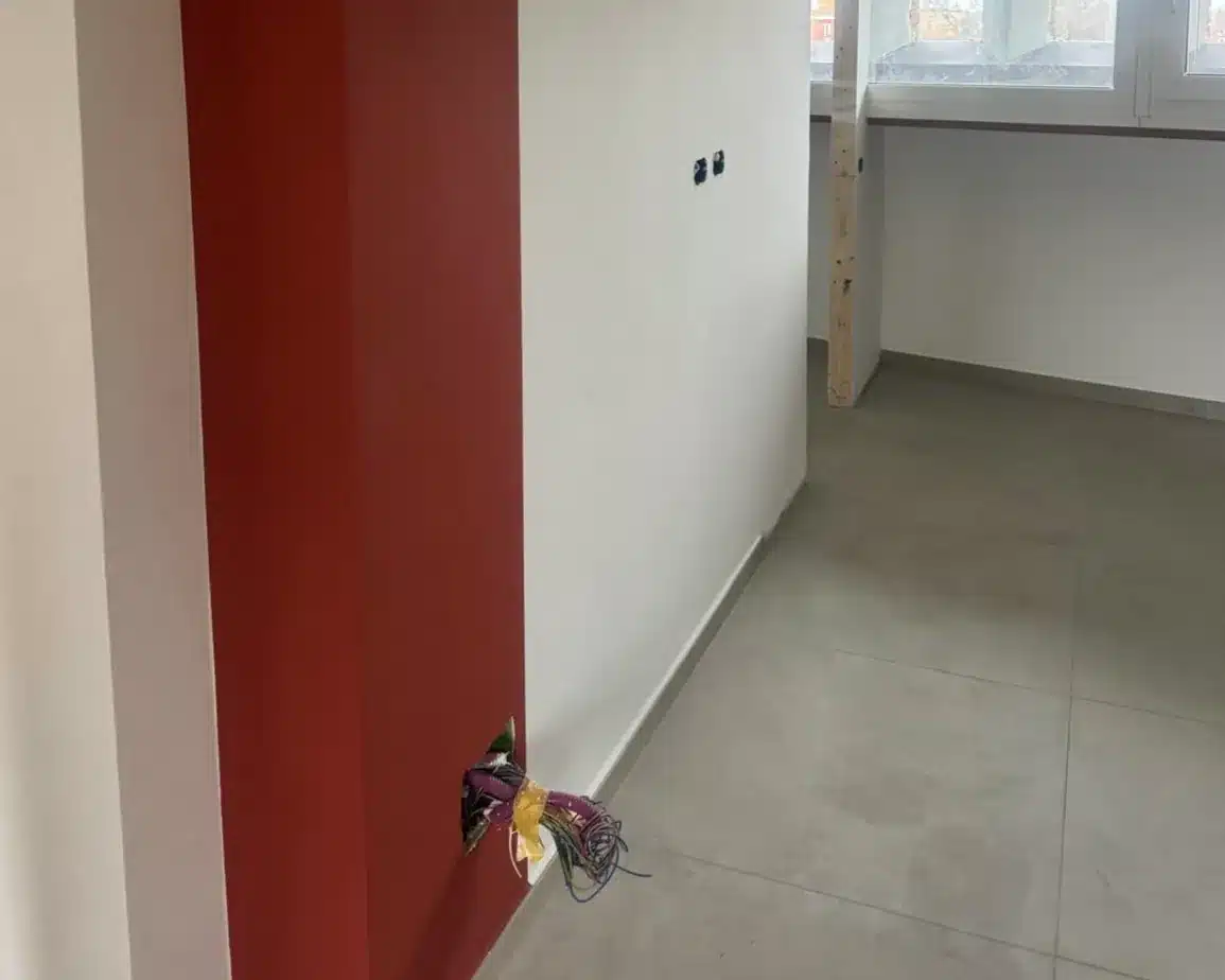 Corridoio di un appartamento ristrutturato con parete rossa e pavimento in gres