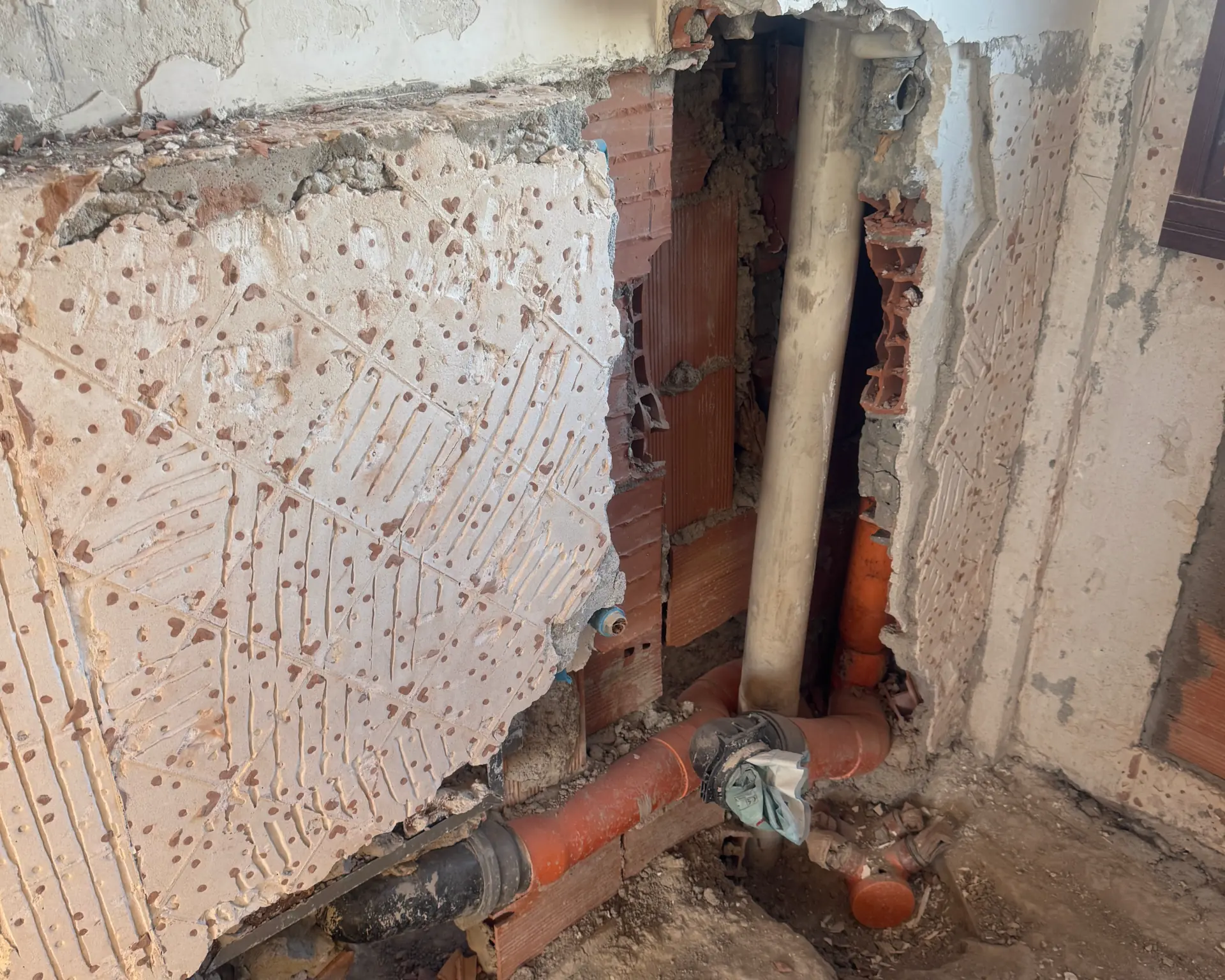 Parete demolita con le vecchie tubazioni di scarico da sostituire
